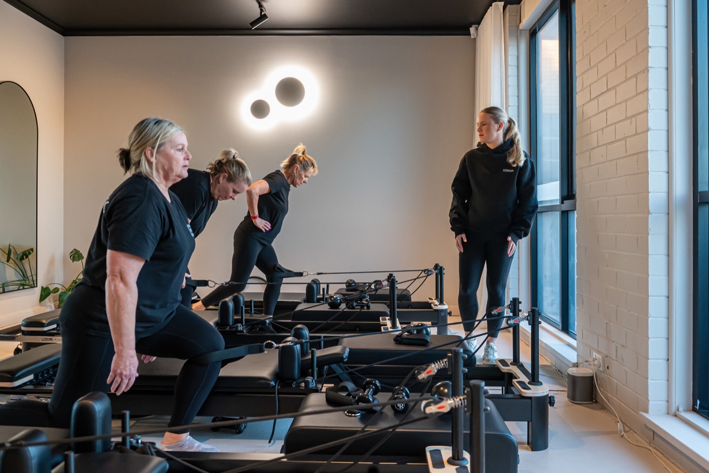 A coach guiding members through a reformer Pilates class